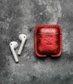 Husă AirPods 2 roșu metalizat vedere laterală, profil, cusătură roșie saddle stitch, logo embossat, piele naturală, canturi vopsite