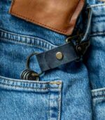 Breloc din piele naturală navy purtat la gaică blugi, context real de utilizare, hardware gold antichizat vizibil