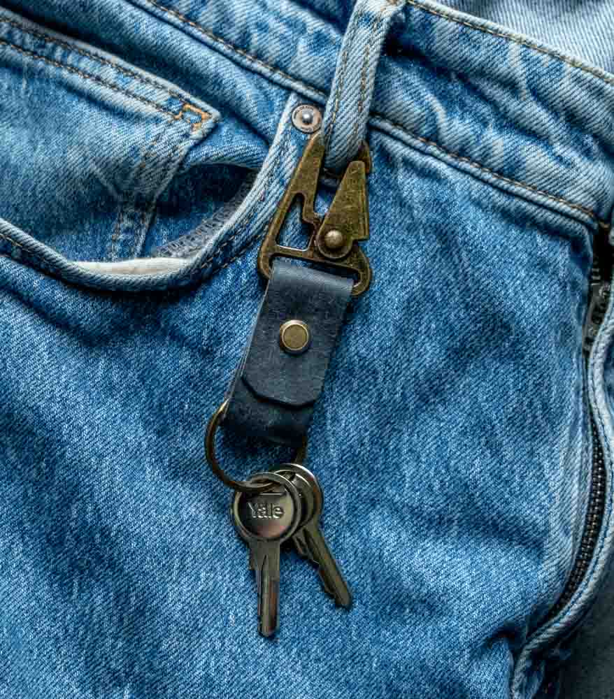 Detaliu breloc piele cu carabină navy prins la gaică blugi, carabină gold antichizat în prindere, piele naturală tăbăcită vegetal