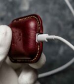 Husă AirPods 2 vișiniu, capsă metalică silver, cusătură manuală bej saddle stitch, canturi vopsite manual, piele naturală