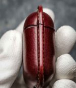 Husă AirPods 2 vișiniu deschisă, interior piele naturală, logo embossat, cusătură bej, capsă silver, canturi vopsite