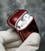 Husă AirPods 2 vișiniu, detaliu logo embossat, cusătură bej manuală, capsă metalică silver, piele naturală tăbăcită vegetal
