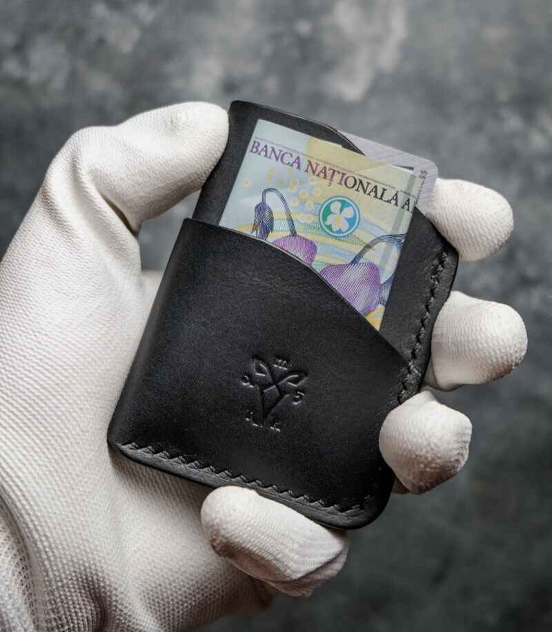Portofel barbati pentru carduri, piele neagră mat, vedere frontală cu bancnotă introdusă în buzunar, logo embosat, cusătură neagră, handmade România