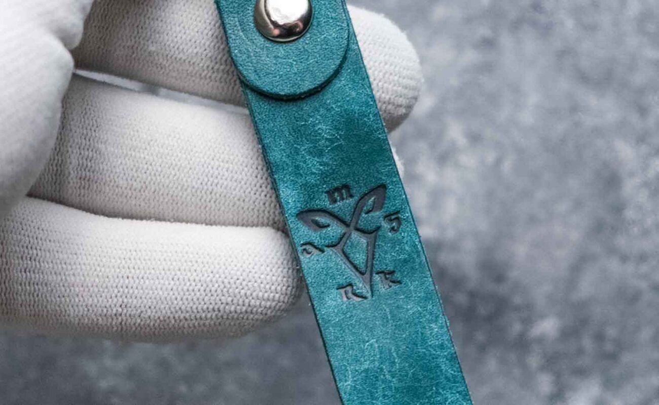 Close-up textură piele naturală turcoaz breloc, inel silver, detaliu hardware