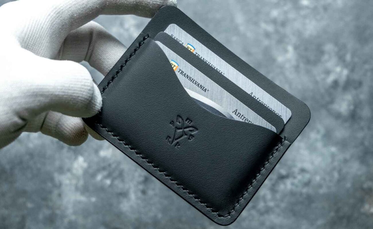 Portofel slim piele naturală neagră ținut în mână, scară de proporție pentru bărbat